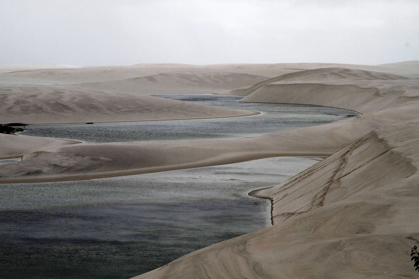 The long shallow sweep of Lagoa Betânia lying between low white dunes under a flat pale sky, the water almost the same tone as the sand