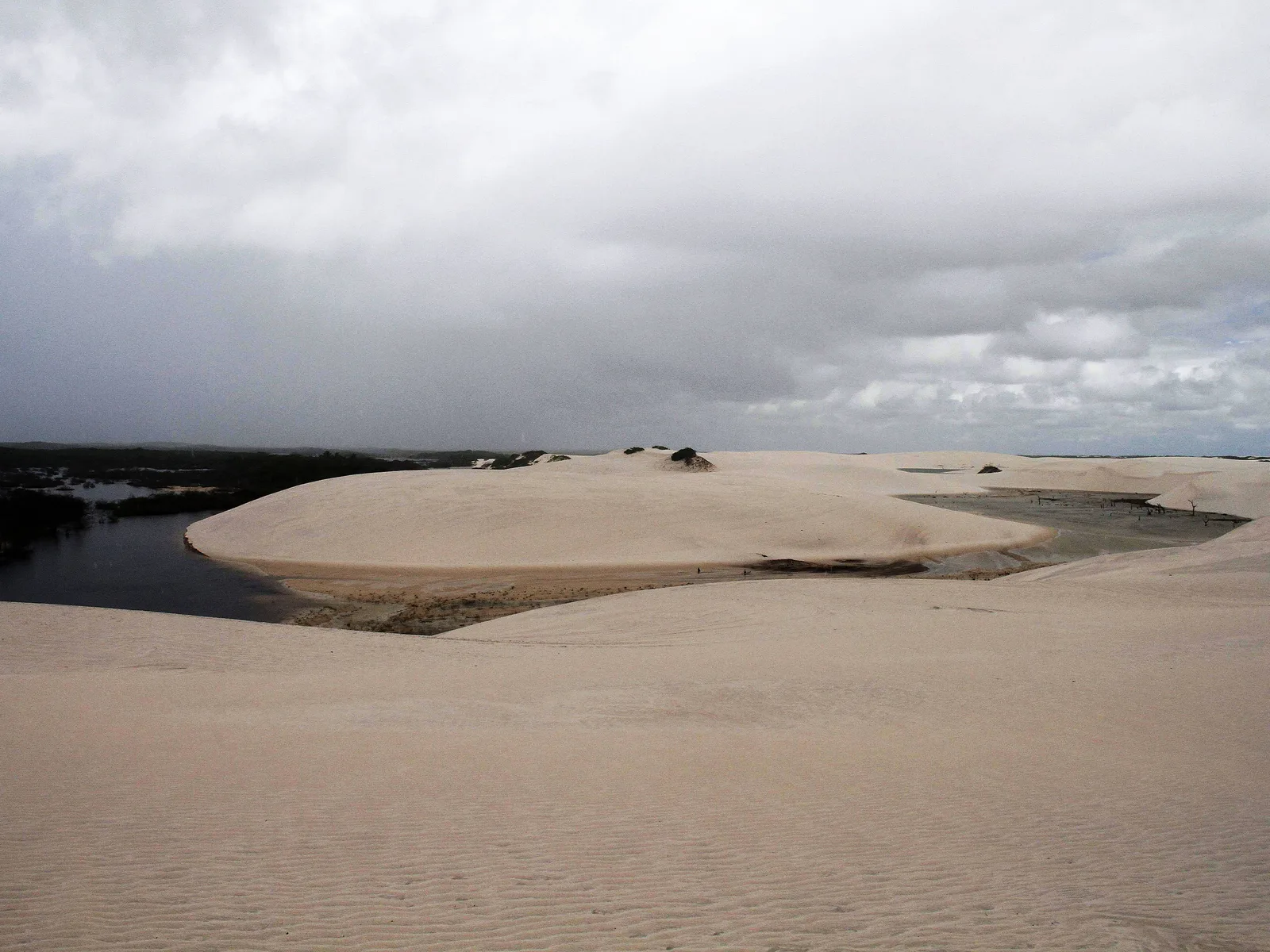 The wide, shallow Lagoa Betânia stretched out between low white dunes at Santo Amaro under a flat gray sky