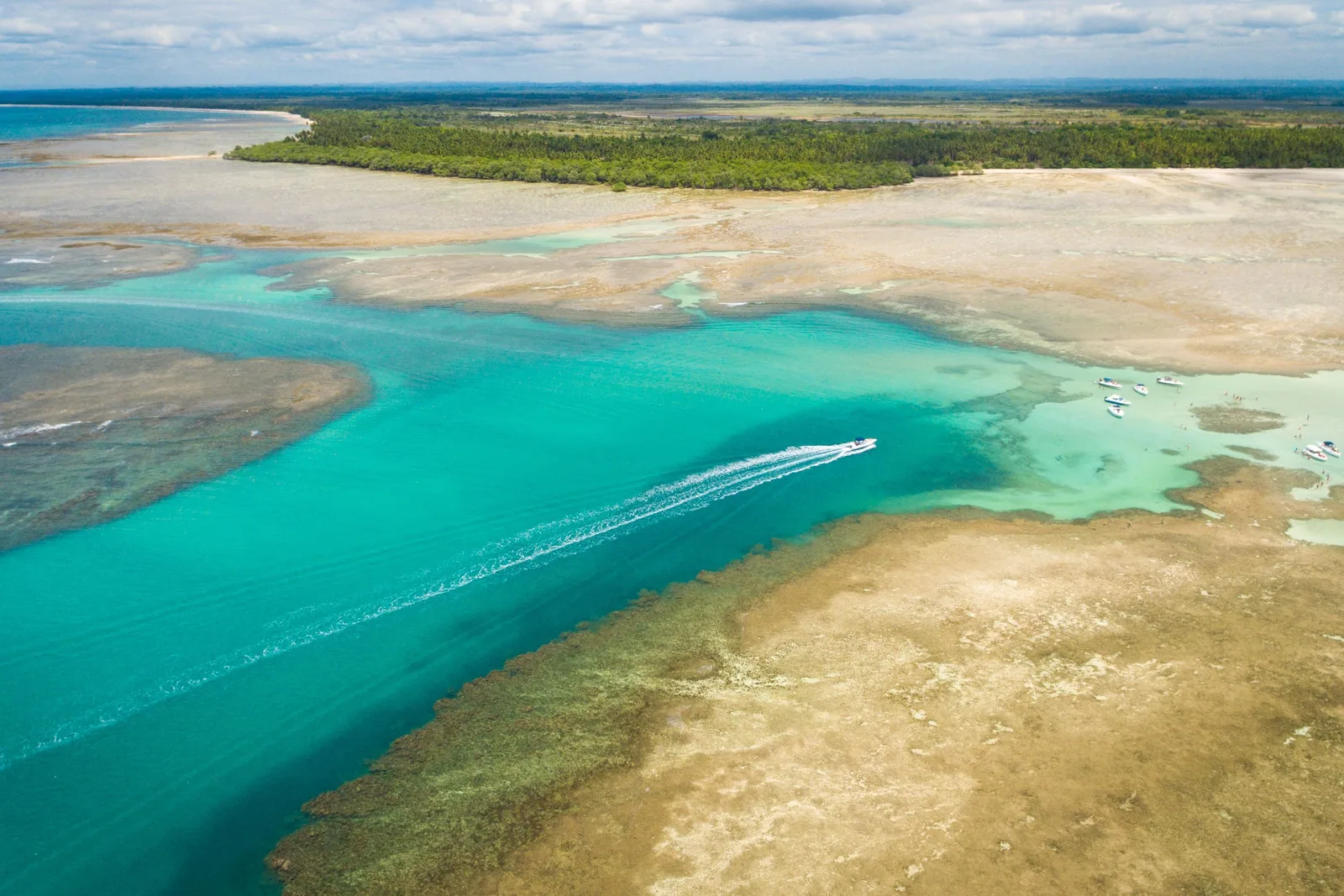 Moreré on Boipeba from the air: a turquoise channel curving between pale sandbanks and reef, with a fringe of green forest along the shore