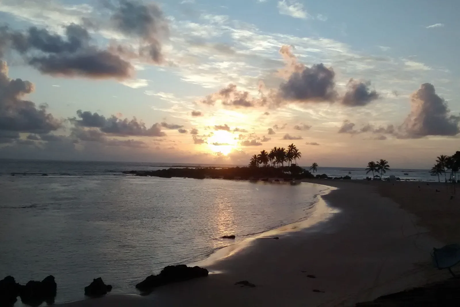 Dawn over the beach at Morro de São Paulo, the sun low behind broken cloud and the wet sand catching the light