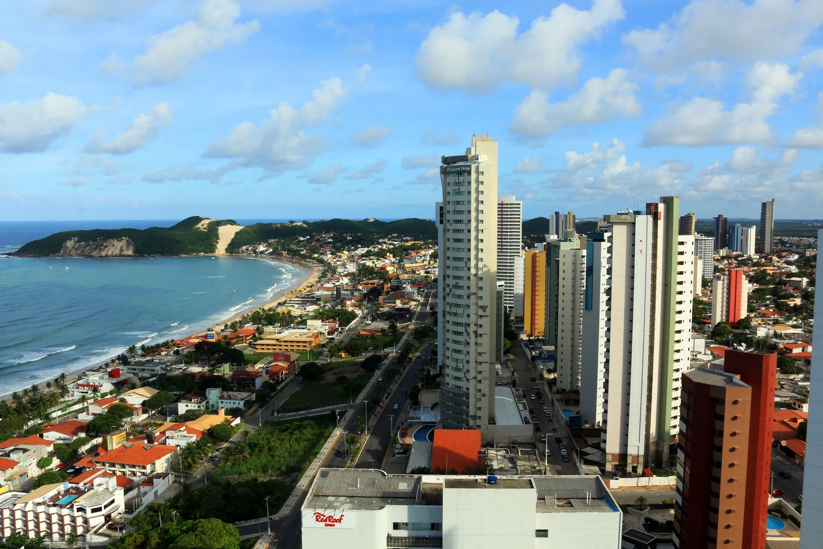 Ponta Negra seen from high beside its apartment towers, the beach curving away to the green headland of Morro do Careca