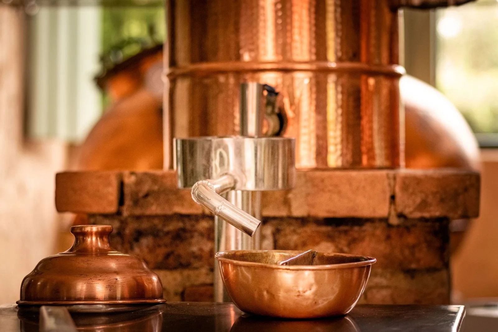 A copper pot still and copper collecting bowls in a working cachaça distillery