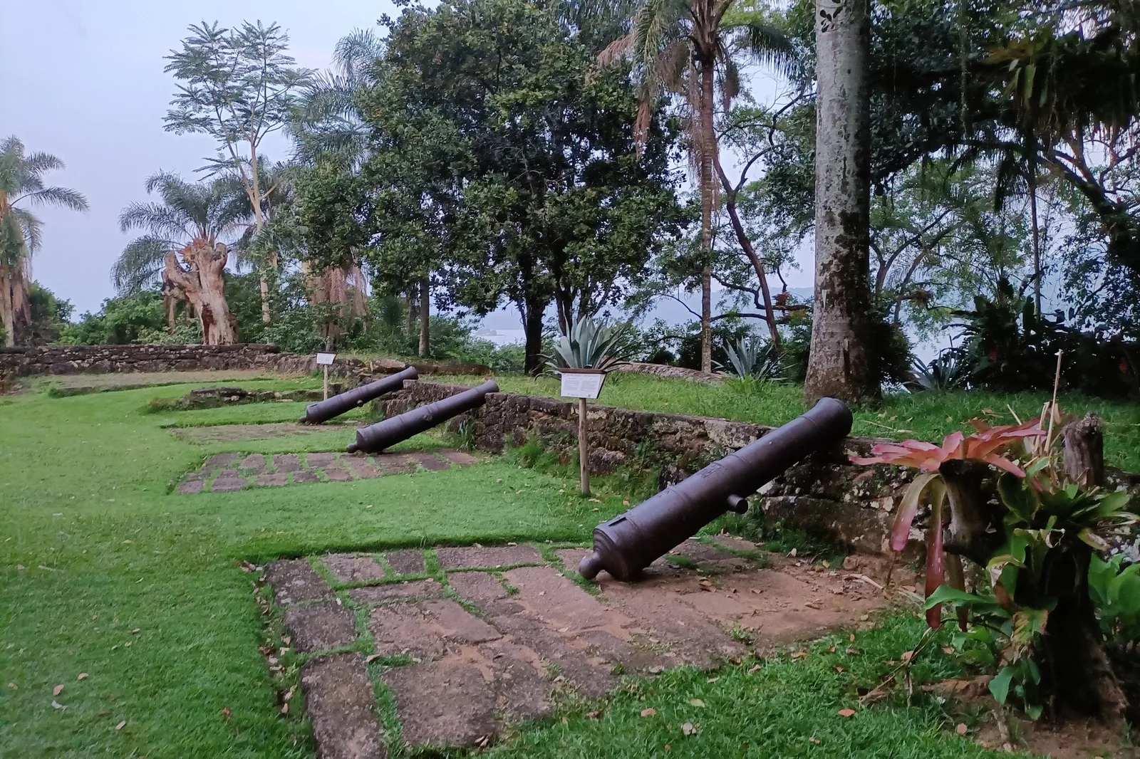 The low stone barracks and sea wall of the Forte Defensor Perpétuo on its wooded headland, old cannon pointing out over Paraty bay
