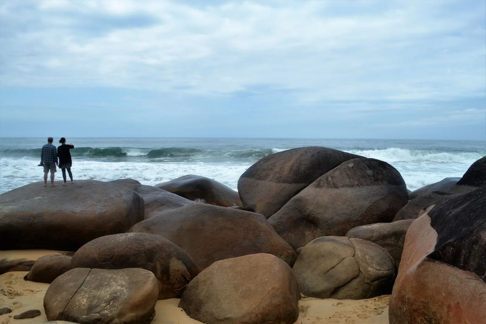 The rocky path between two of Trindade’s beaches, walkers picking their way over granite boulders at the water’s edge with the next arc of sand opening up ahead and forest coming down to the shore