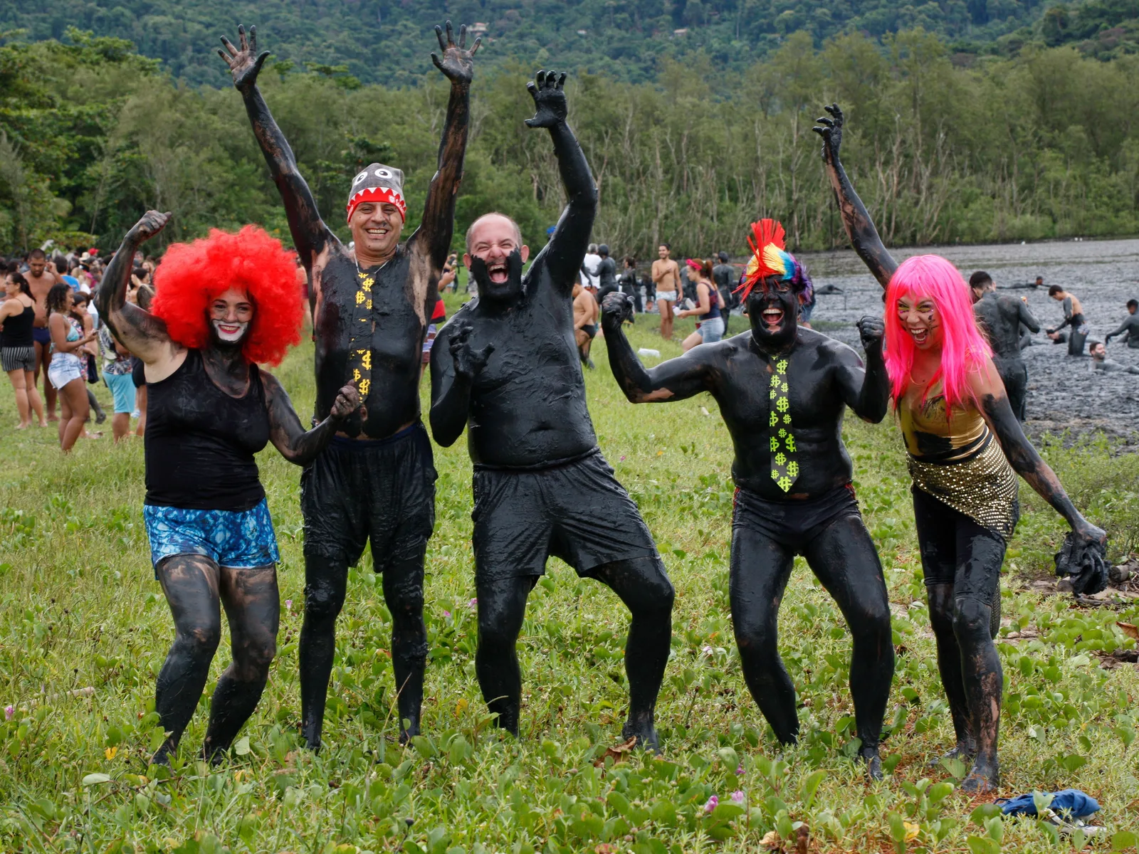 Revelers at the Bloco da Lama in Paraty covered head to foot in gray mangrove mud, wearing vines and rags and shouting, packed together on the beach