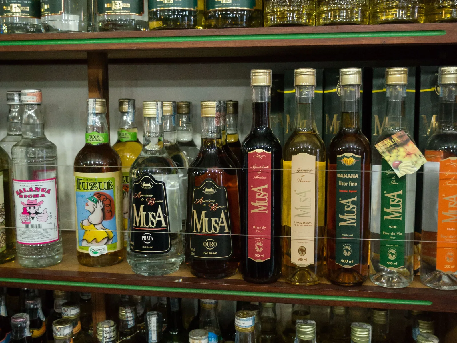 Shelves of labeled cachaça bottles lined up in a Paraty shop