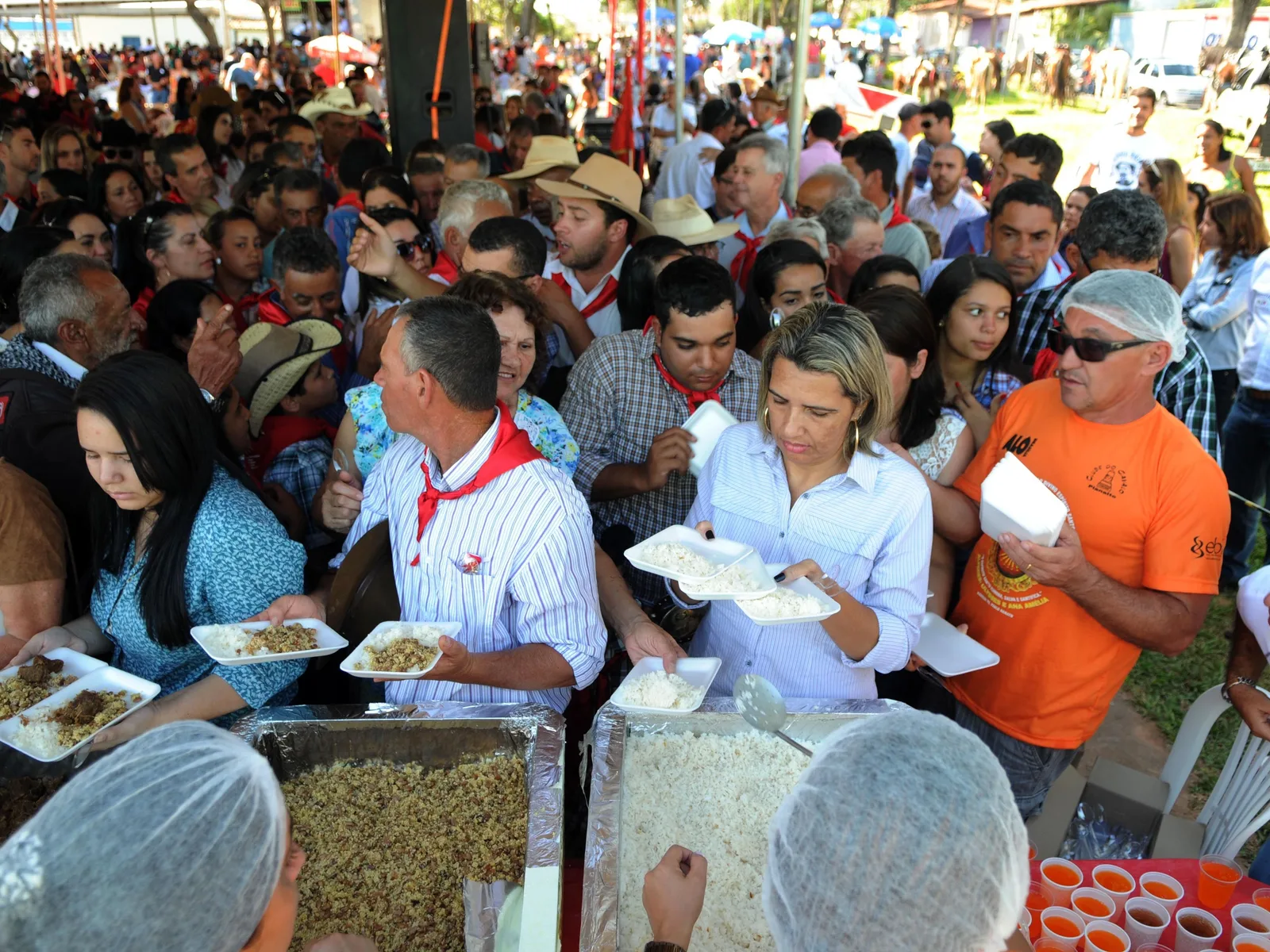 Crowds gathered at a Festa do Divino Espirito Santo, plates being handed out at the communal meal that closes the festival