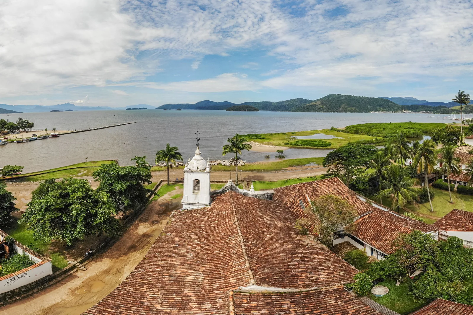 Looking over old tile rooftops and a small church tower toward the islands of Paraty Bay