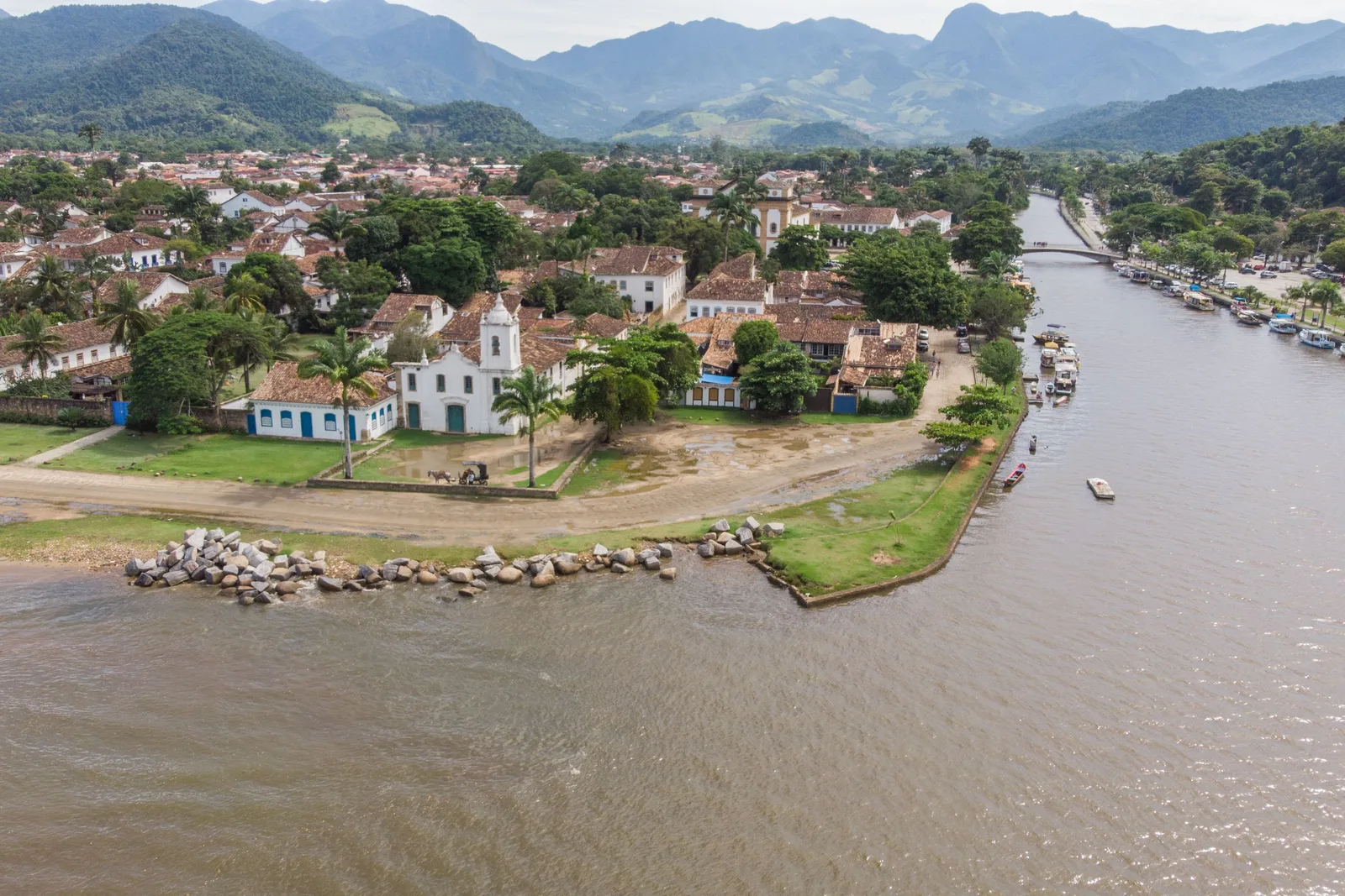 Paraty from the air: the white colonial town on its point where the river meets the bay, green mountains behind