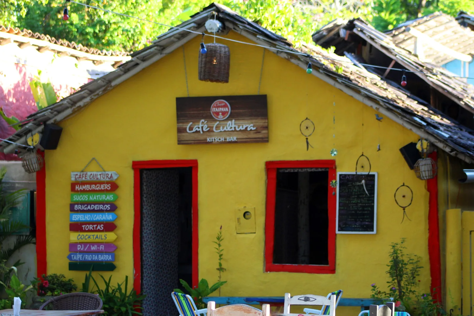 A yellow cottage on Trancoso’s Quadrado with a Café Cultura sign, red-framed door and windows, a painted menu board and small tables set out in front