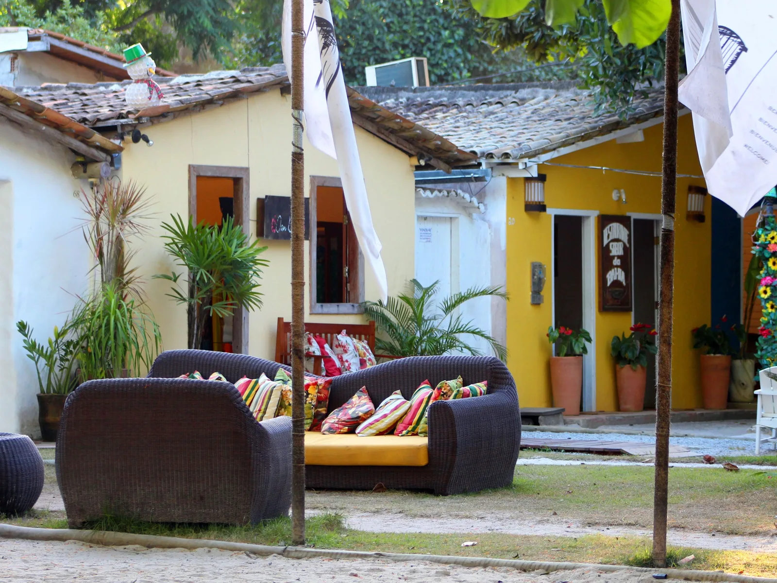 Low painted cottages along one side of Trancoso’s Quadrado, white and yellow with tiled roofs, white flags on tall poles and cushioned outdoor sofas set out on the grass in front