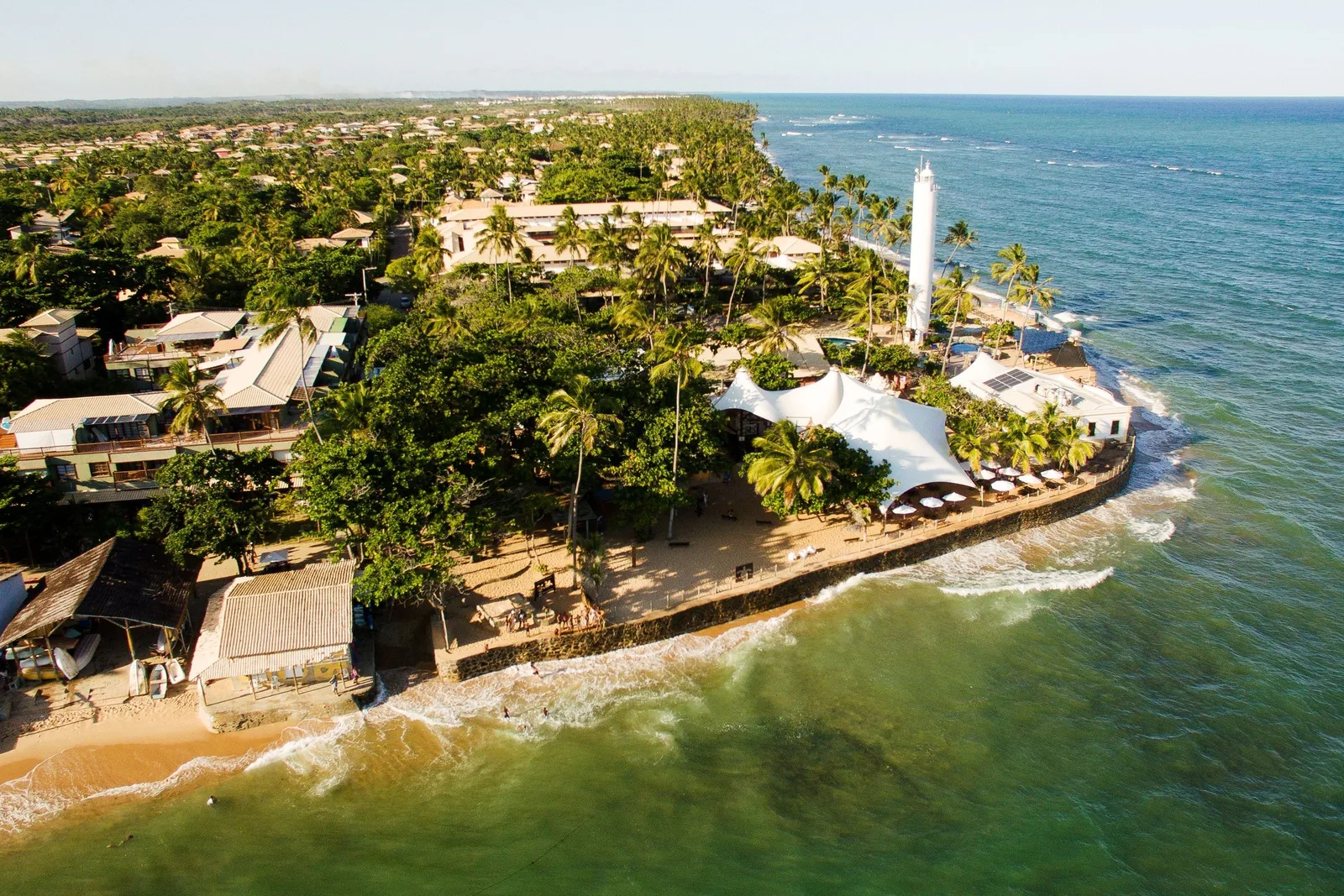 Praia do Forte from the air: the lighthouse on its point, the village under the palms and the reef in clear green water