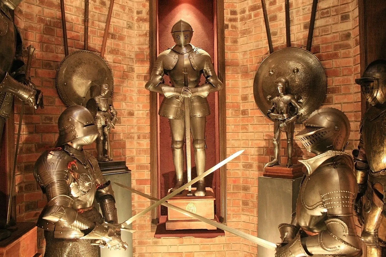 Suits of plate armor and crossed swords displayed in a brick-arched niche in the arms gallery of the Instituto Ricardo Brennand