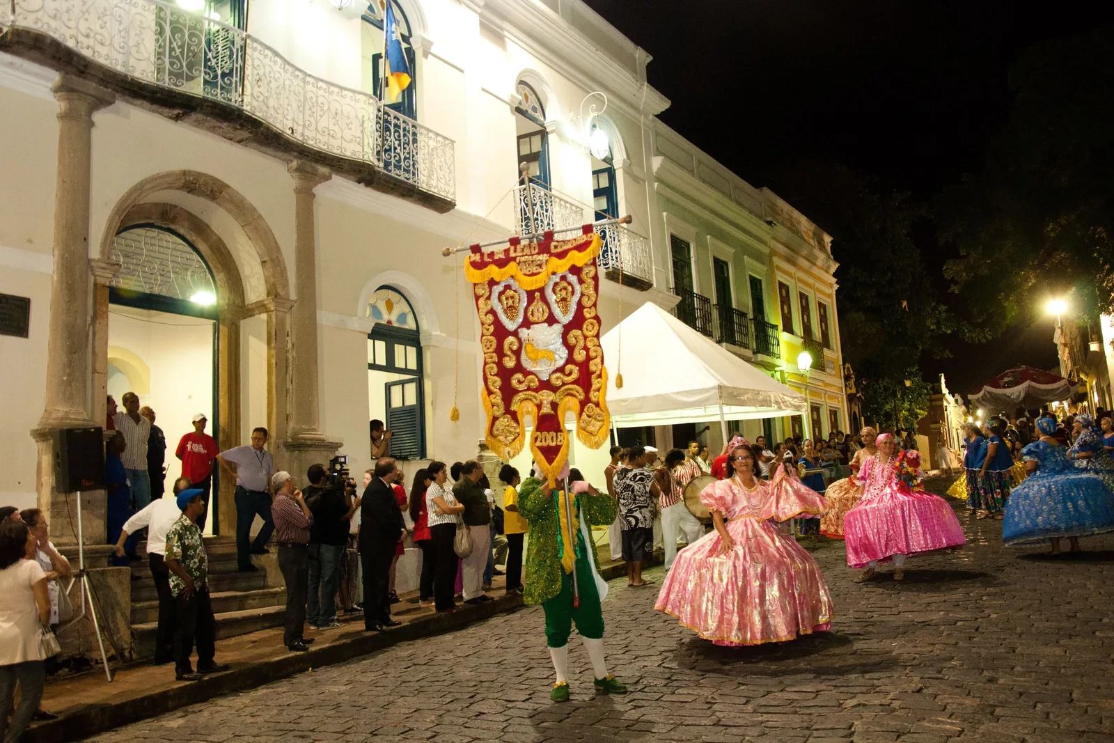 Maracatu performers in embroidered court dress outside a colonial building in Olinda at night