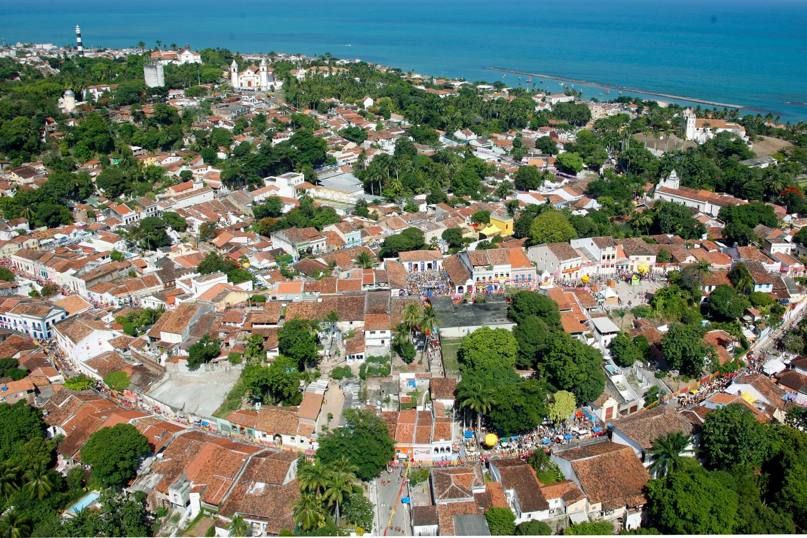 Olinda from above: terracotta roofs and church towers packed among mango and palm trees, with the Atlantic beyond