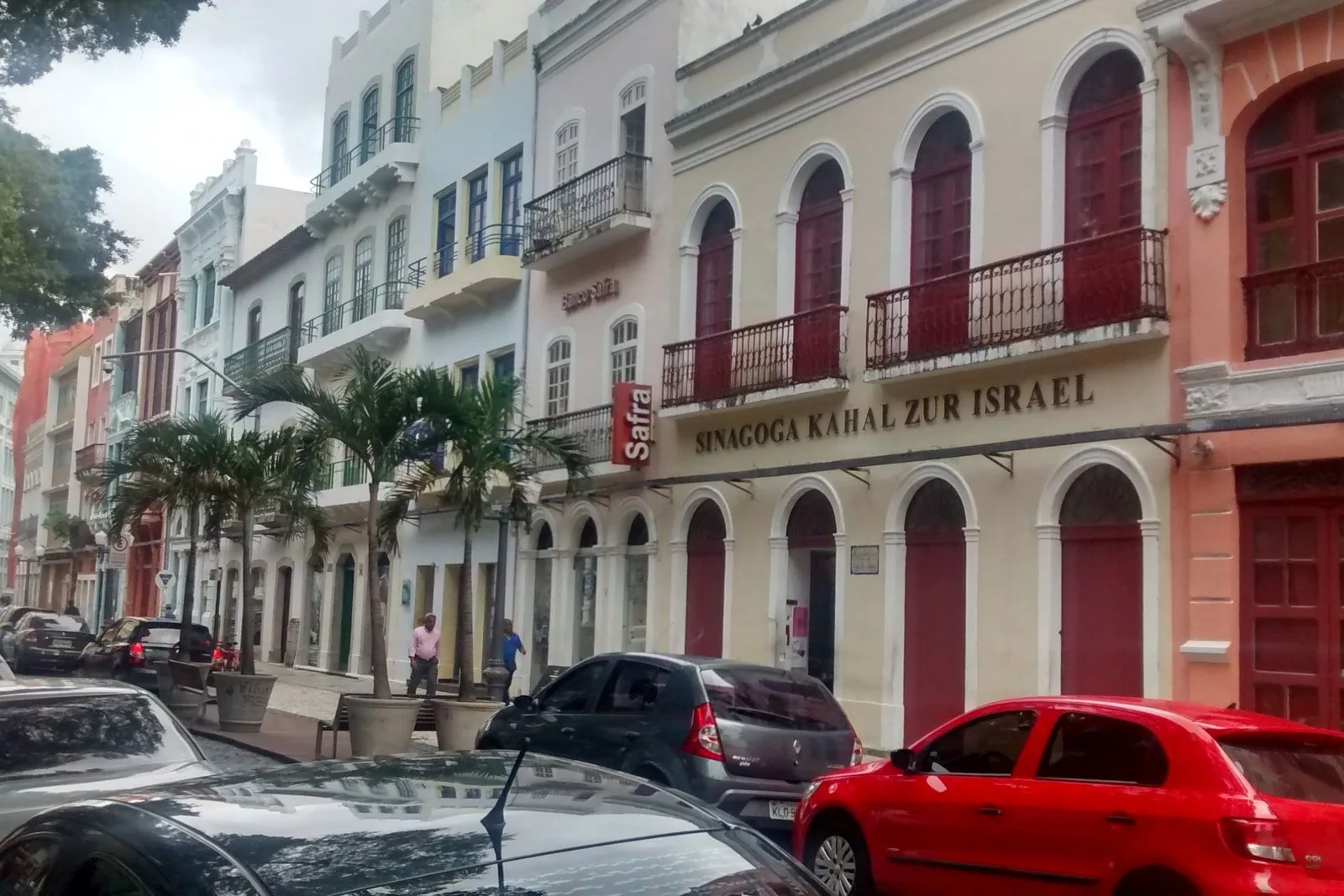 The Rua do Bom Jesus in Recife Antigo: a row of tall colonial townhouses in cream, blue, pink and terracotta with iron balconies, the Kahal Zur Israel synagogue among them with its name lettered across the front