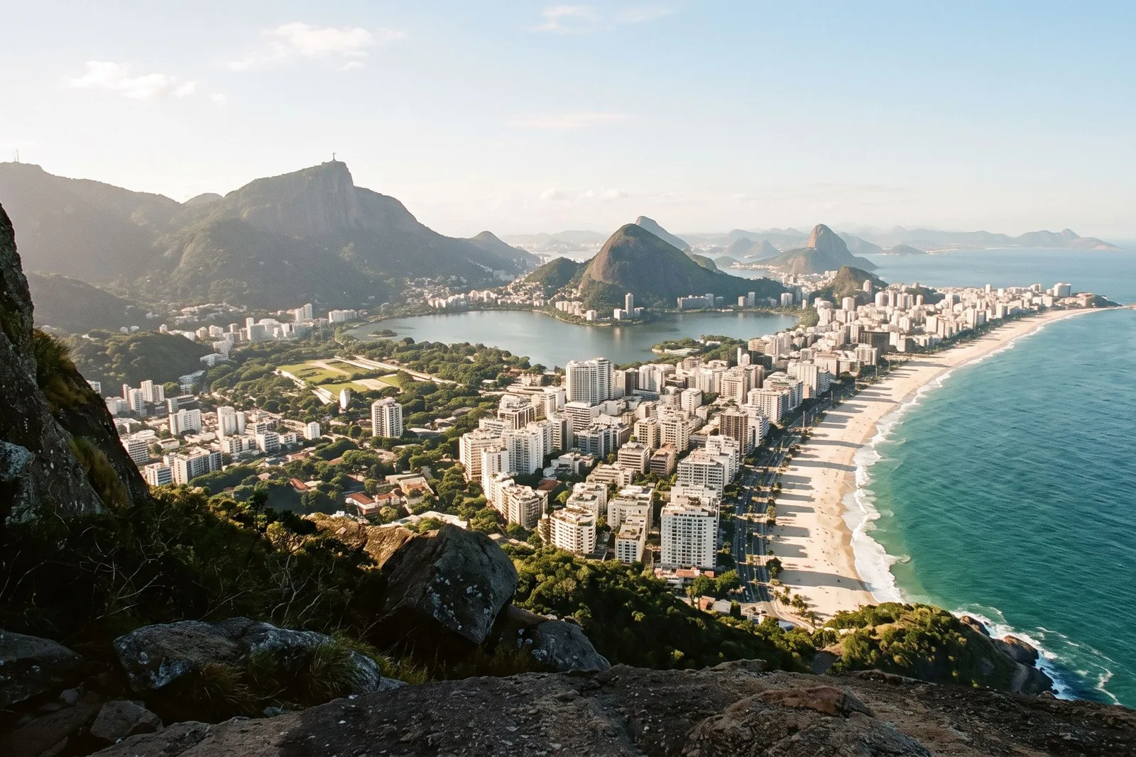 The view from high on Dois Irmãos looking back along the curve of Leblon and Ipanema, the Lagoa behind the buildings and the granite peaks of Rio in the haze beyond