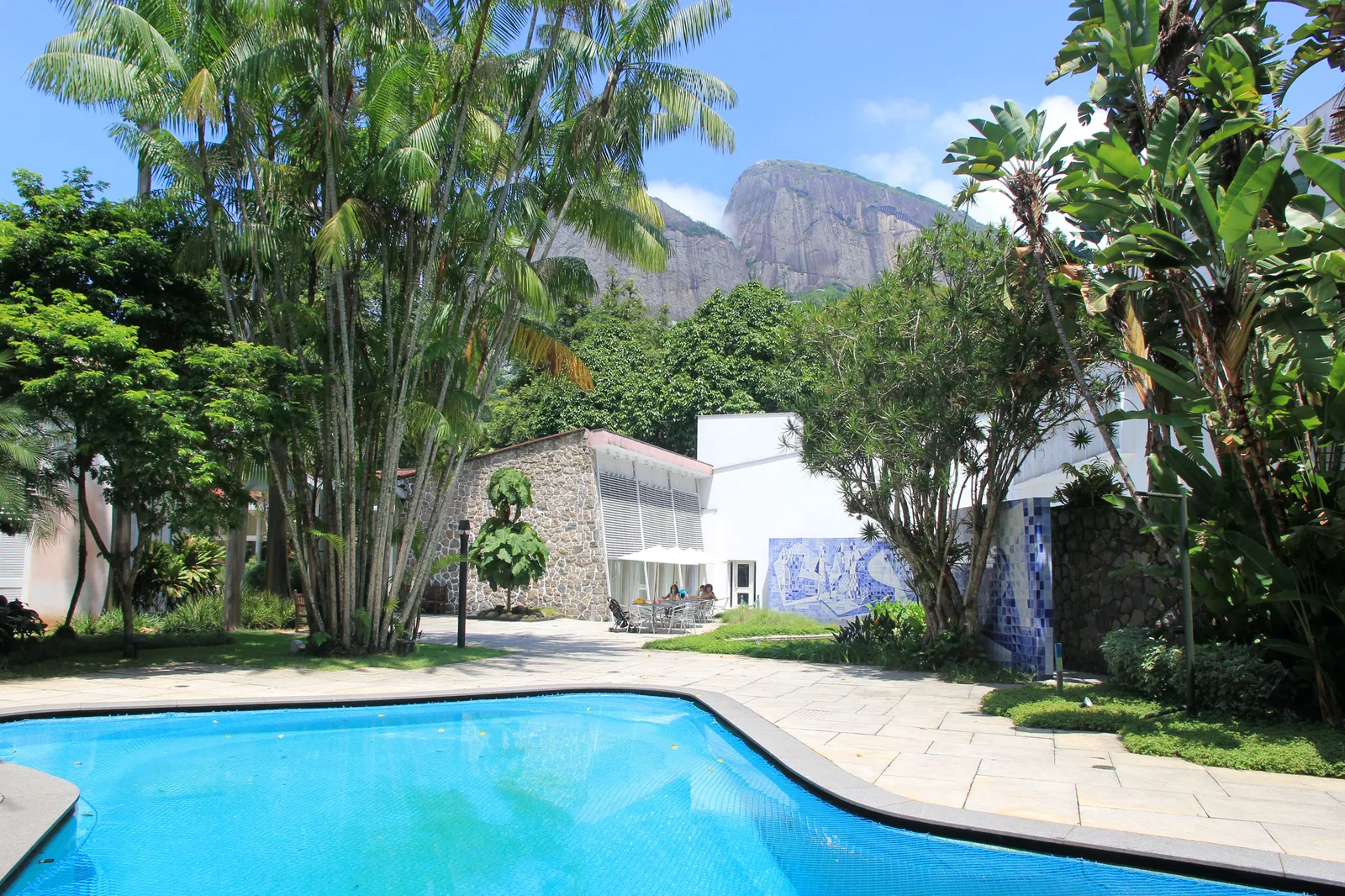 The Instituto Moreira Salles in Gávea: a low modernist house behind a long pool and planted garden, forested peaks rising behind