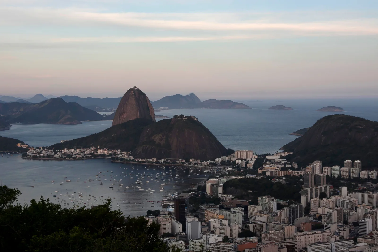 Sugarloaf Mountain and the mouth of Guanabara Bay from above at dusk, the city lights just coming on