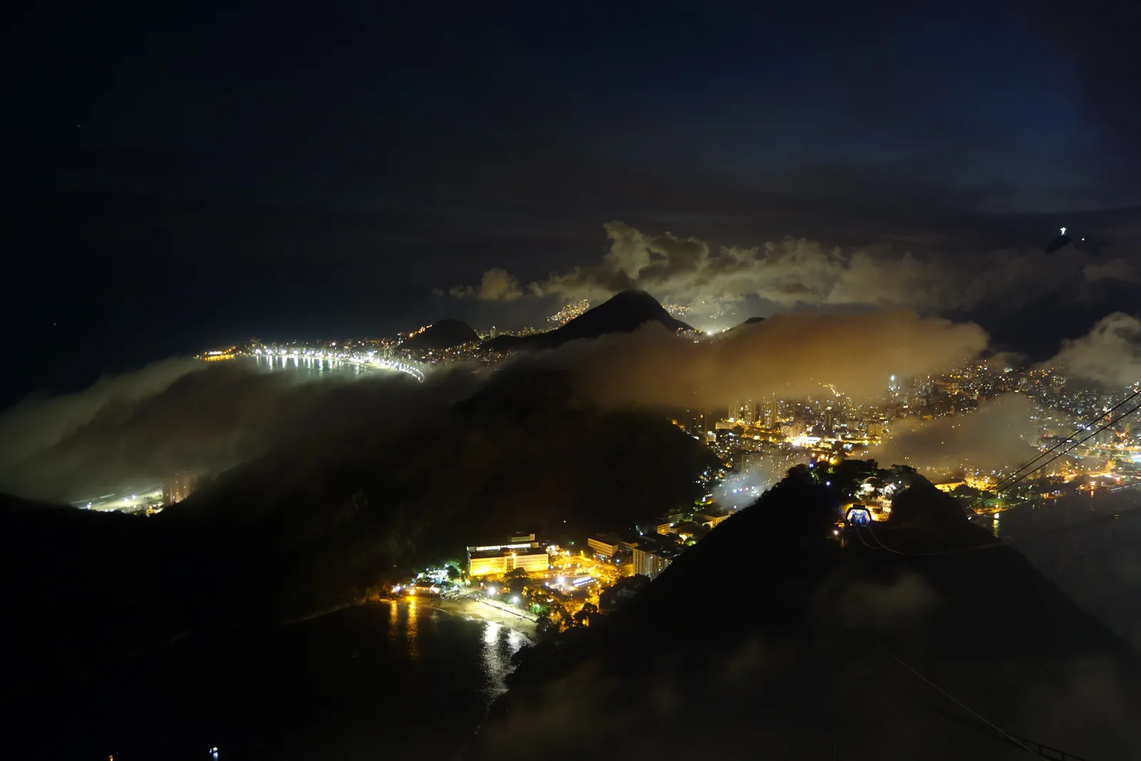 Dusk from high above Rio, the lights of the shoreline coming on below a dark headland