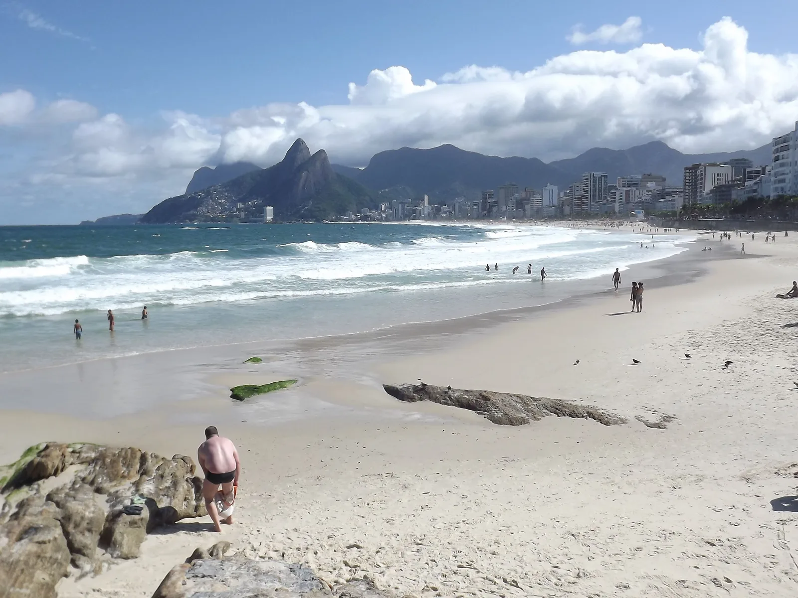 Ipanema beach seen from the rocks at Arpoador, surf running up the sand and the twin Dois Irmãos peaks closing the far end