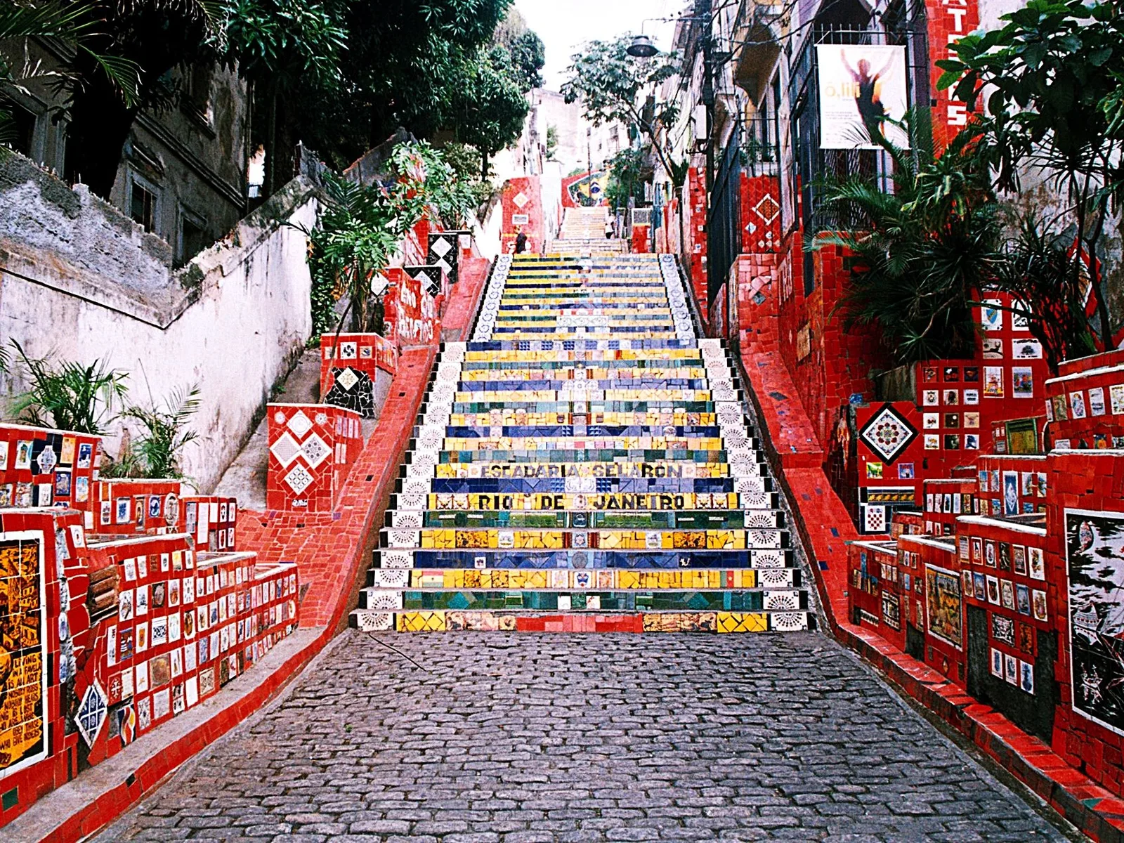 The Selarón steps rising between buildings, the walls either side packed with red tiles and the stairs themselves in blue, yellow and green