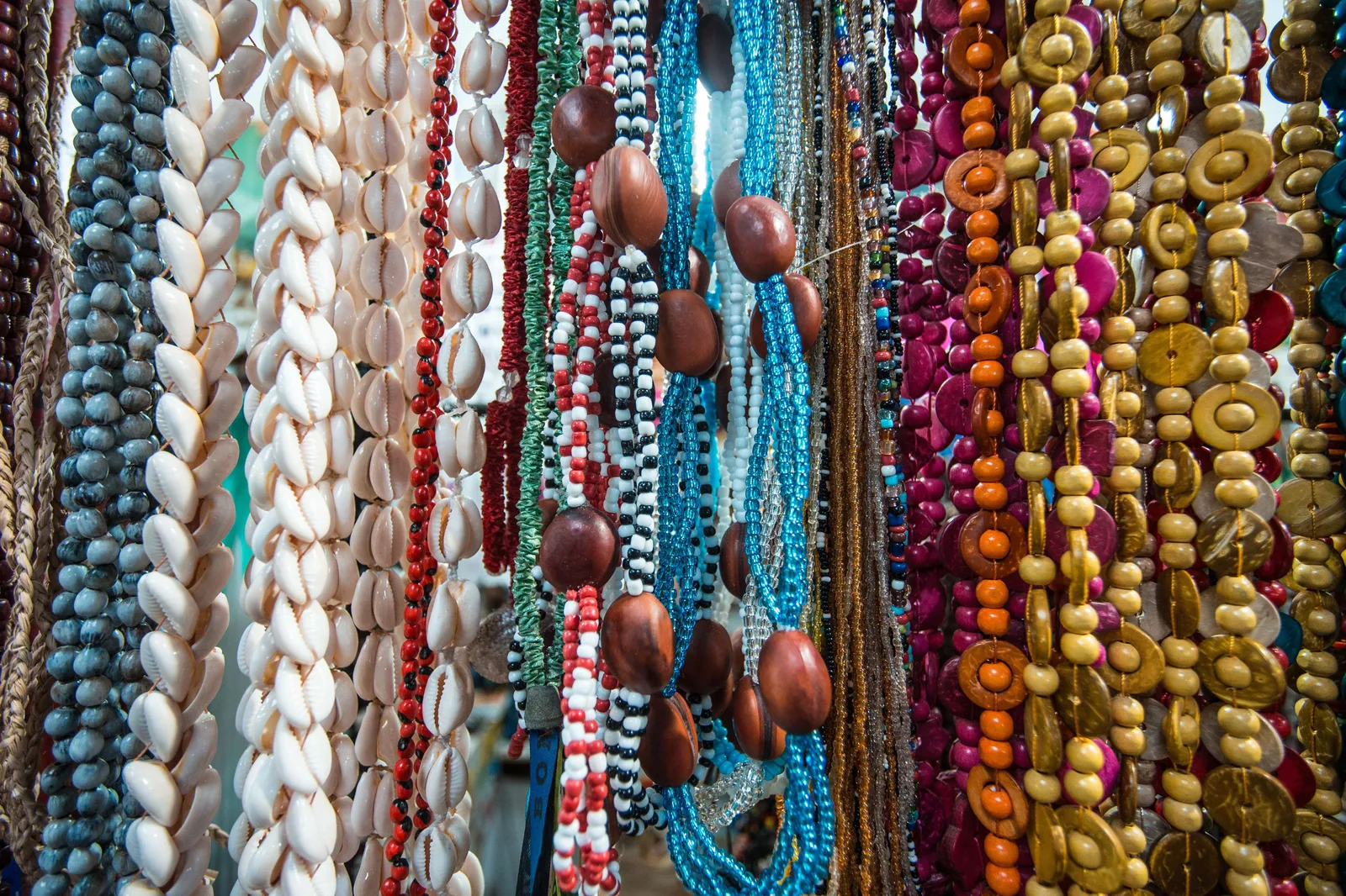 Strands of colorful beaded necklaces hanging in rows at a stall in the Mercado Modelo
