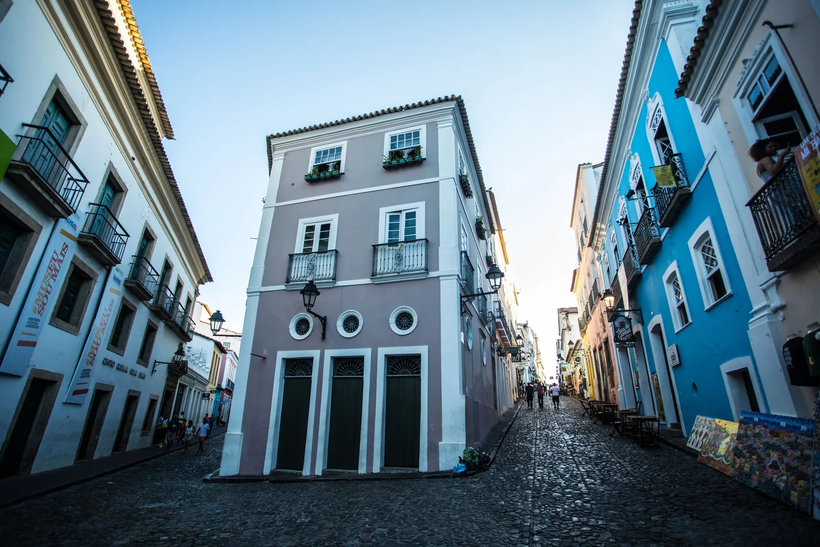 A pale blue colonial building at the end of a cobbled Pelourinho street, painted houses on both sides