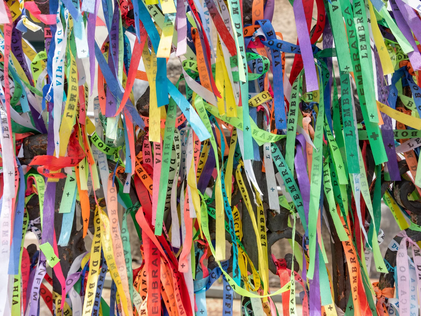 Close on the ironwork outside the Igreja do Senhor do Bonfim, packed with hundreds of knotted cotton ribbons in every color, each one printed “Lembrança do Senhor do Bonfim da Bahia”