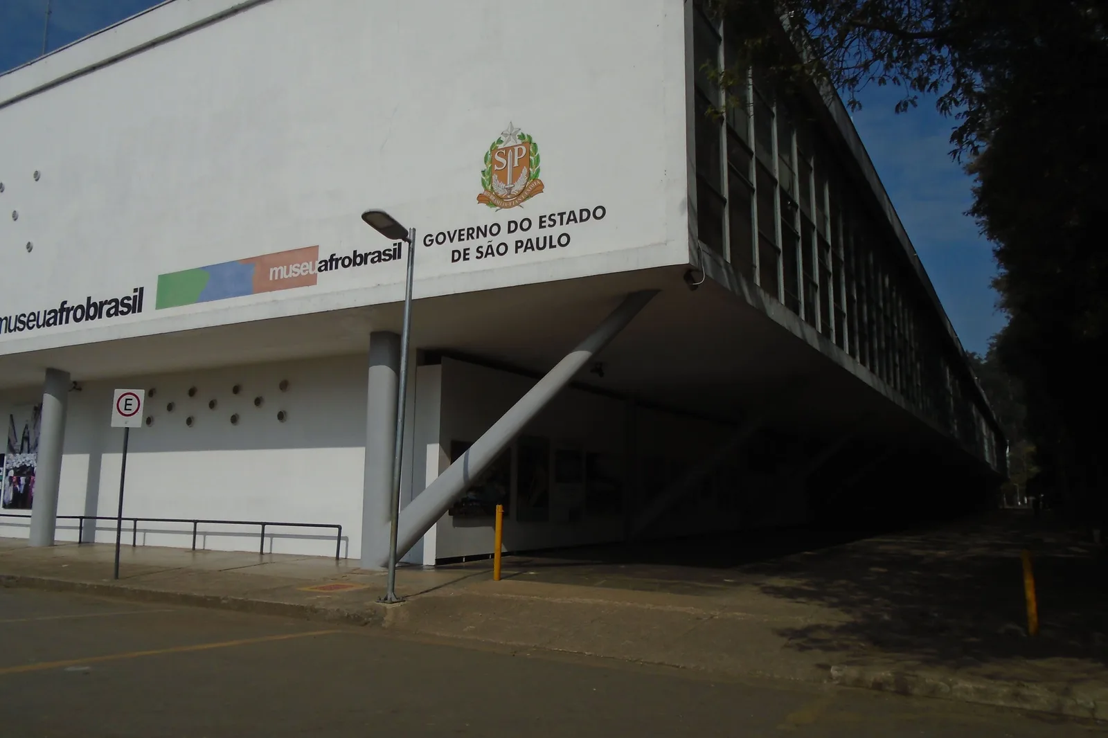 The Museu Afro Brasil in Ibirapuera: the long white concrete underside of Niemeyer’s pavilion raised on piers above an empty forecourt, the museum’s name on a banner across the end wall