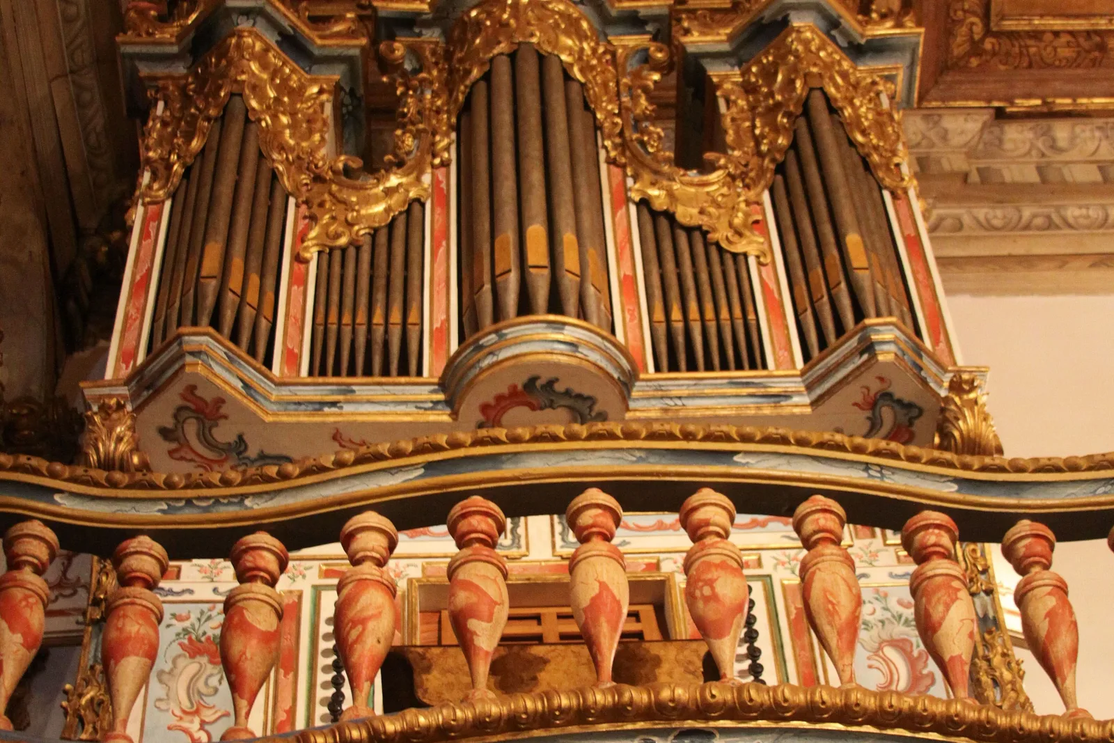 The eighteenth-century pipe organ of the Matriz de Santo Antônio in its gilded case, ranks of metal pipes rising behind carved and gold-leafed scrollwork and turned wooden balusters