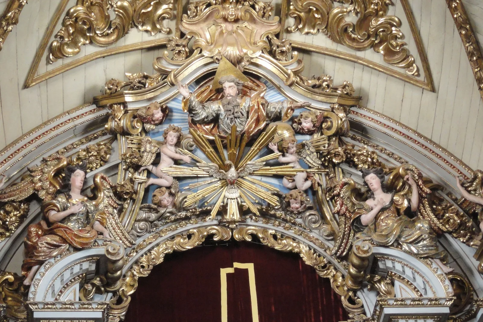 The gilded rococo frontispiece above the high altar of the Catedral Basílica de Nossa Senhora do Pilar, a mass of carved gold scrollwork, painted cherubs and a crowned central medallion