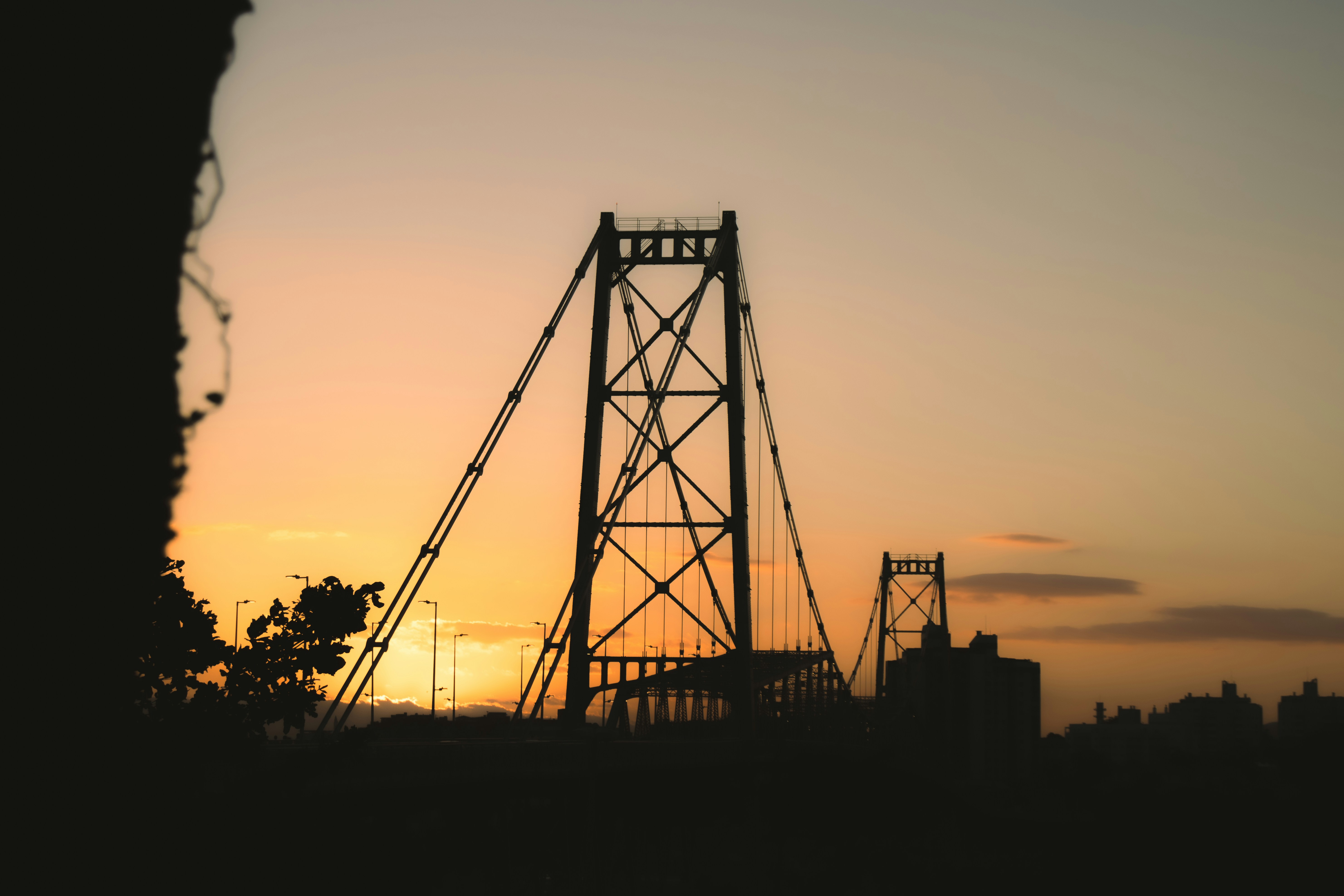 The Hercílio Luz Bridge in silhouette against a warm Florianópolis sunset